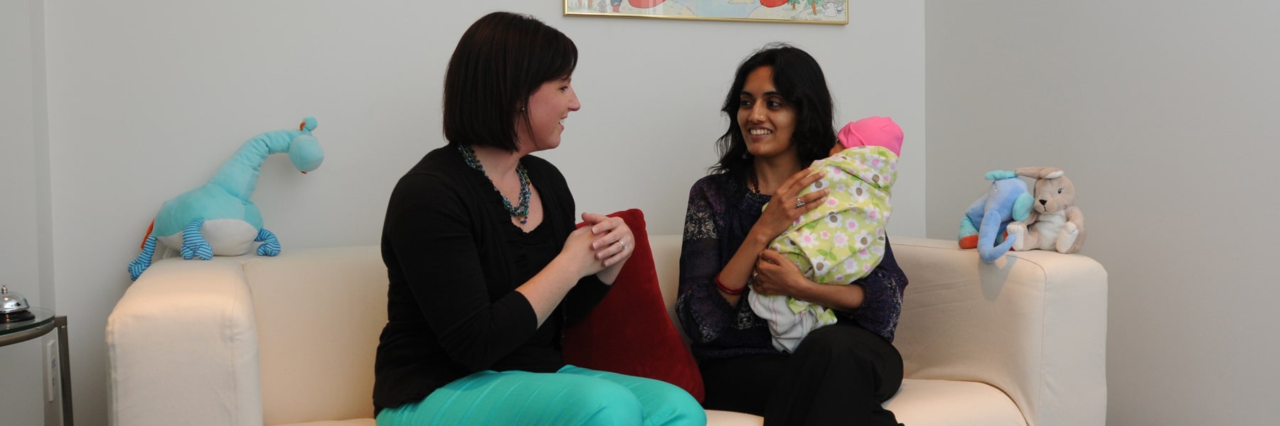 female consultant on couch with mother swaddling baby