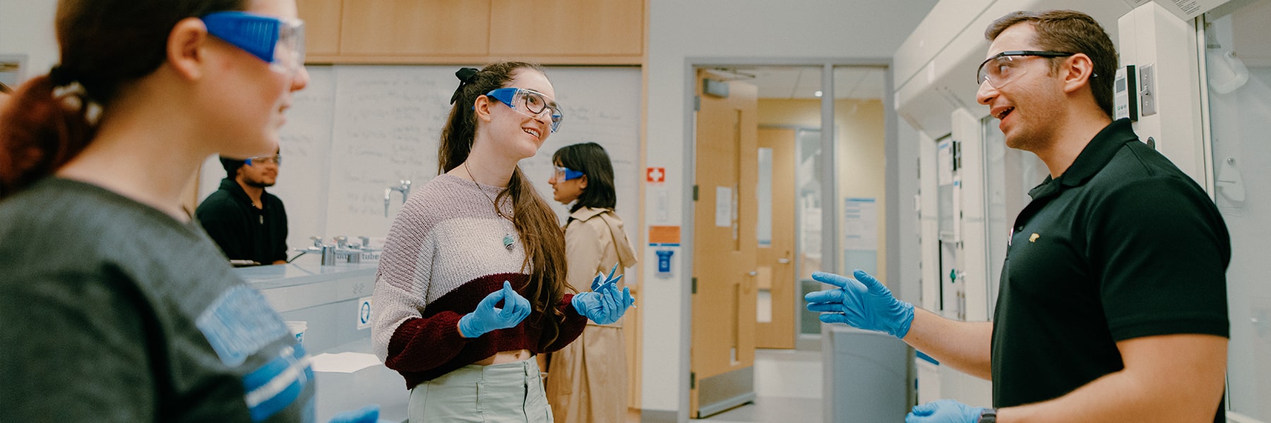 Students work in lab talking to professor.