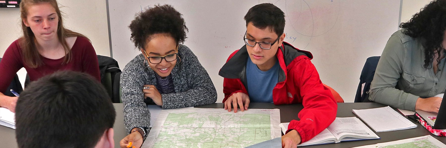 Students view large map on a conference room table.