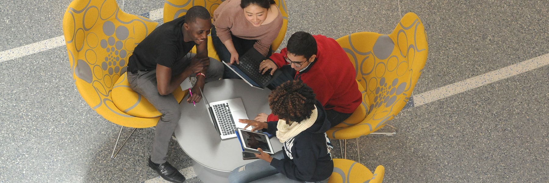 Students view laptops in lobby of Integrated Sciences Complex.