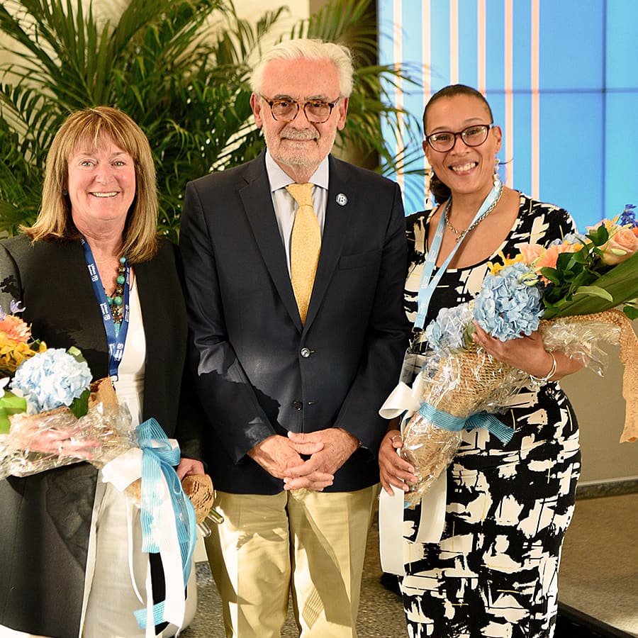 two women holding bouquets pose with the chancellor.