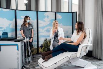 Two FlossTime dental providers next to one patient in a dental chair, conversing.