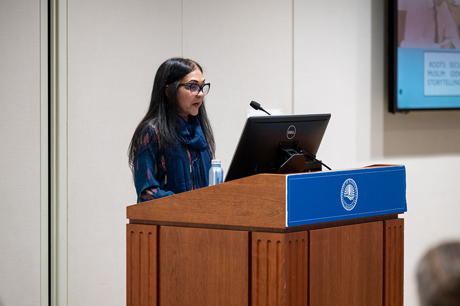 Elora Chowdhury stands at a podium, giving her lecture