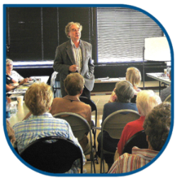 OLLI course facilitator standing in front of students in a classroom