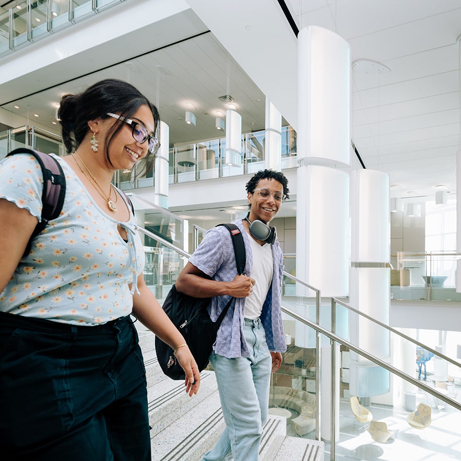 Two UMass Boston students walk down the stairs in the Integrated Sciences Complex